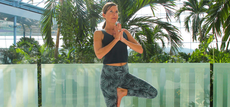 Frau in Yoga Position auf der Sky Lounge mit Ausblick auf das Palmenparadies