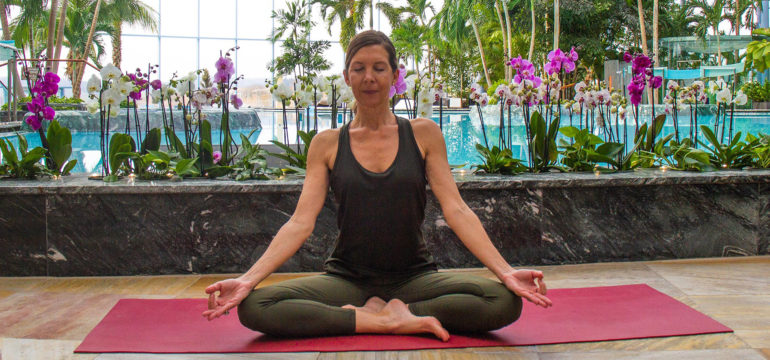 Frau in Yoga Position vor der großen Lagune im Palmenparadies