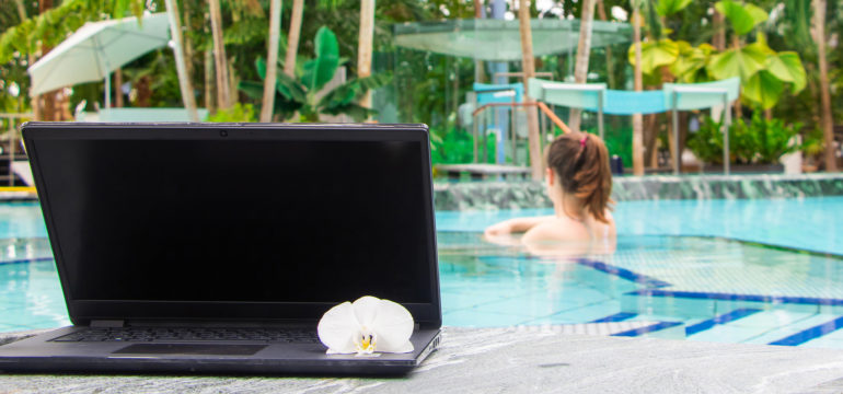 Frau in Whirlpool mit Laptop im Palmenparadies